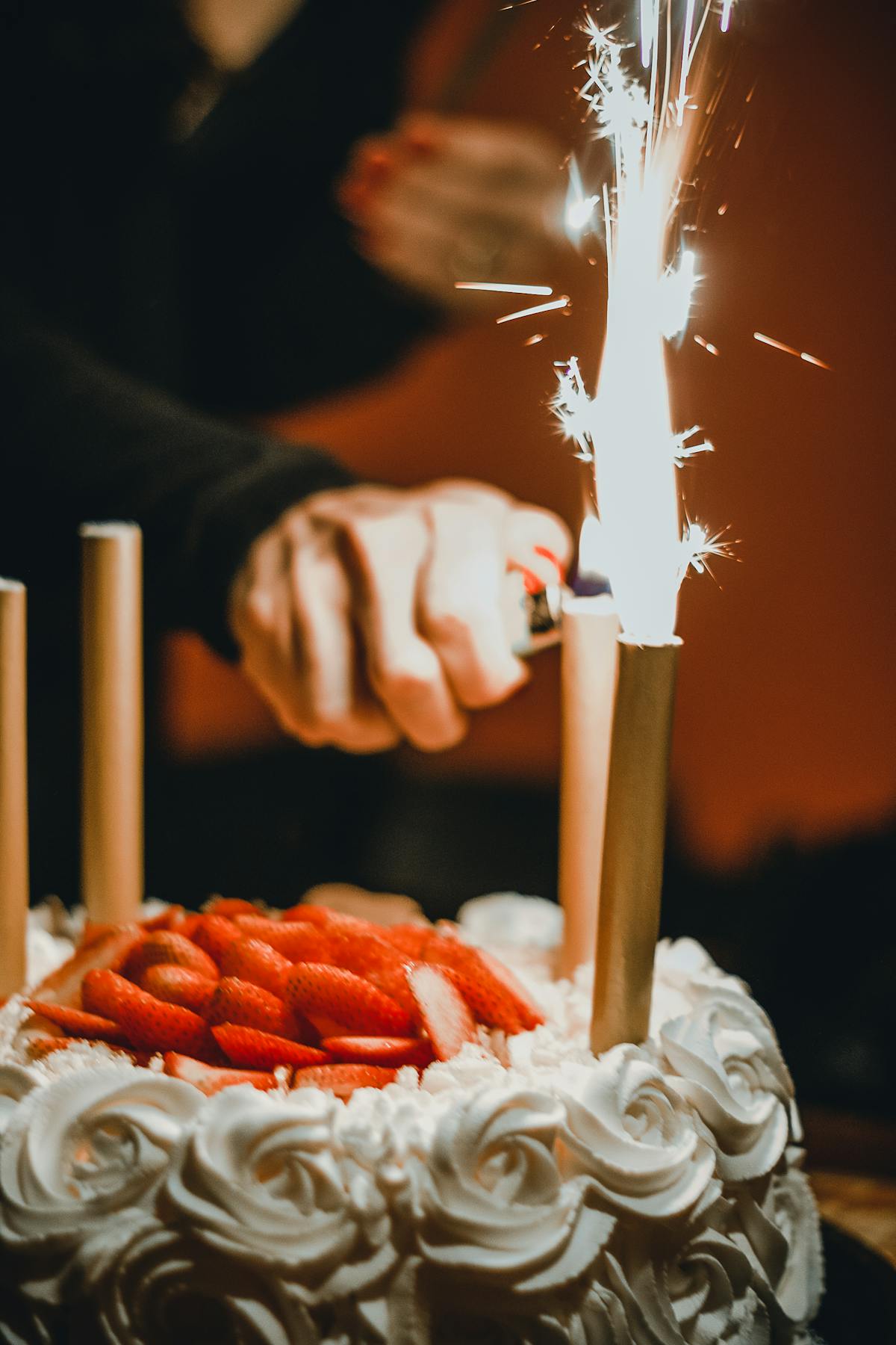 Dog wearing a colorful party hat sitting next to a small birthday cake with streamers in the background
